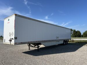 A white trailer parked in the middle of a lot.