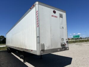 A white trailer parked on the side of a road.