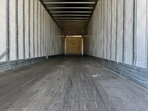 A large trailer with wooden floors and white walls.