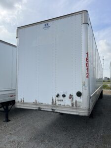 White Puma trailer parked outdoors with visible wear on the lower side.