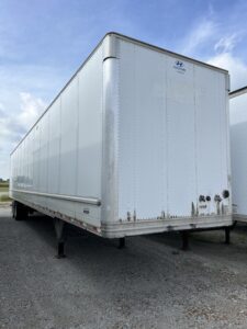 White dry van trailer parked outdoors on a cloudy day.