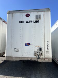 Rear view of a white cargo trailer with text and a small logo.