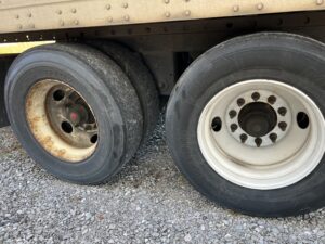Two truck tires, one severely damaged and flat, the other intact and inflated.
