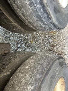 Close-up of two worn-out vehicle tires on gravel ground.