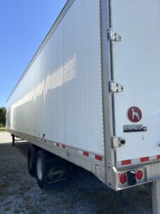 White semi-trailer truck parked outdoors with clear sky.