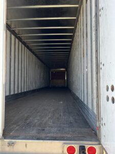 Empty cargo container with metal walls and wooden floor.